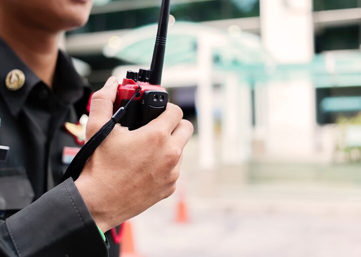A person in a work uniform holding a walkie talkie radio